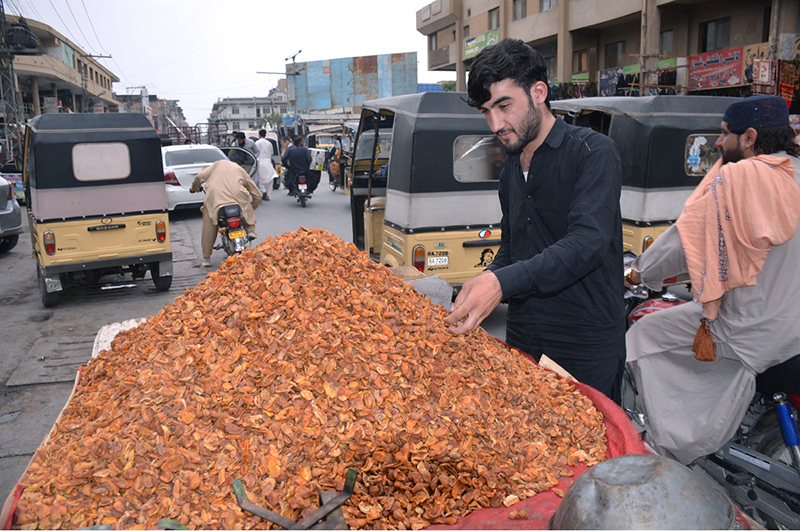 A customer purchases dried apricots from a roadside vendor at Meezan Chowk in the provincial capital