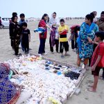 A woman sells seashells and other ornamental items at the beachside to visitors
