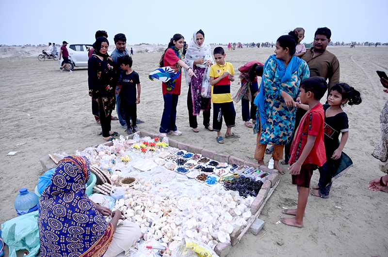 A woman sells seashells and other ornamental items at the beachside to visitors
