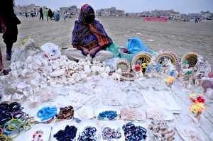 A woman sells seashells and other ornamental items at the beachside to visitors
