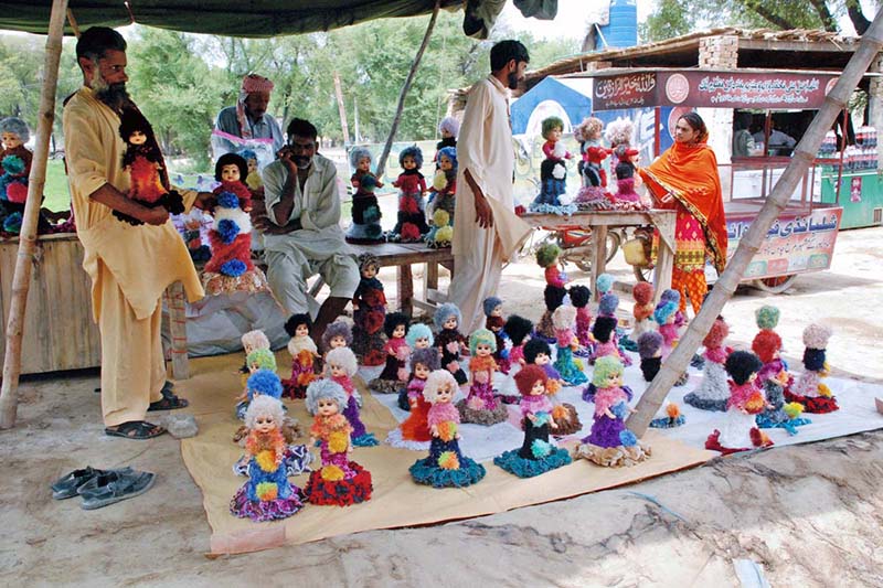 People selecting dolls for their little ones from a roadside vendors’ stall