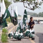 A young vendor arranging and displaying national flags to attract the customers along Faisal Avenue in connection with Independence Day celebrations