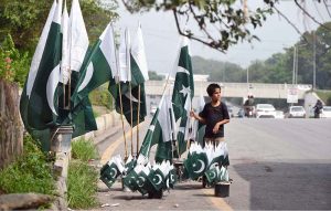 A young vendor arranging and displaying national flags to attract the customers along Faisal Avenue in connection with Independence Day celebrations