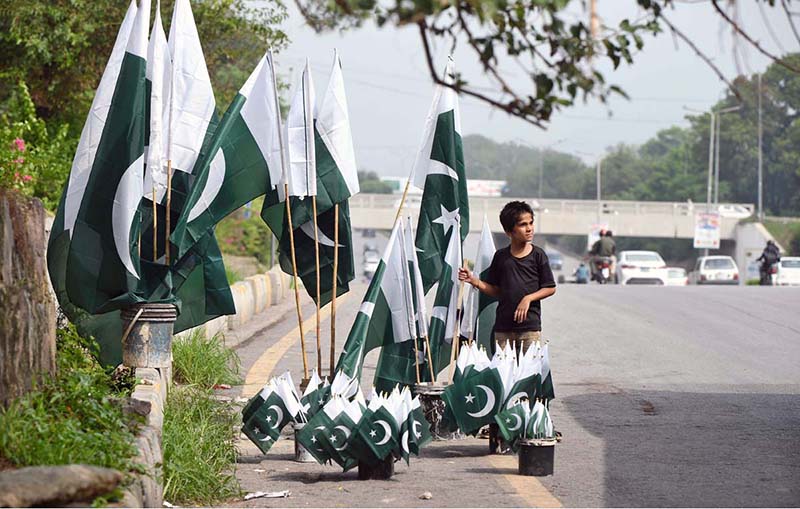 A young vendor arranging and displaying national flags to attract the customers along Faisal Avenue in connection with Independence Day celebrations
