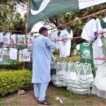 A vendor arranged and displayed children's clothes containing Pakistani flags to attract customers at a stall along the Expressway as part of Independence Day celebrations