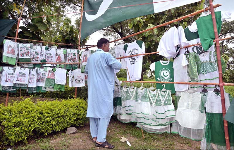 A vendor arranged and displayed children's clothes containing Pakistani flags to attract customers at a stall along the Expressway as part of Independence Day celebrations