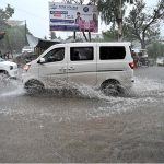 Vehicles passing through rain water accumulated on IJP Road after heavy rainfall in the Federal Capital