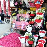 A vendor arranges and displays colourful flower bouquets garlands and flower petals to attract customers at Banni Chowk