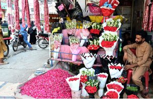 A vendor arranges and displays colourful flower bouquets garlands and flower petals to attract customers at Banni Chowk