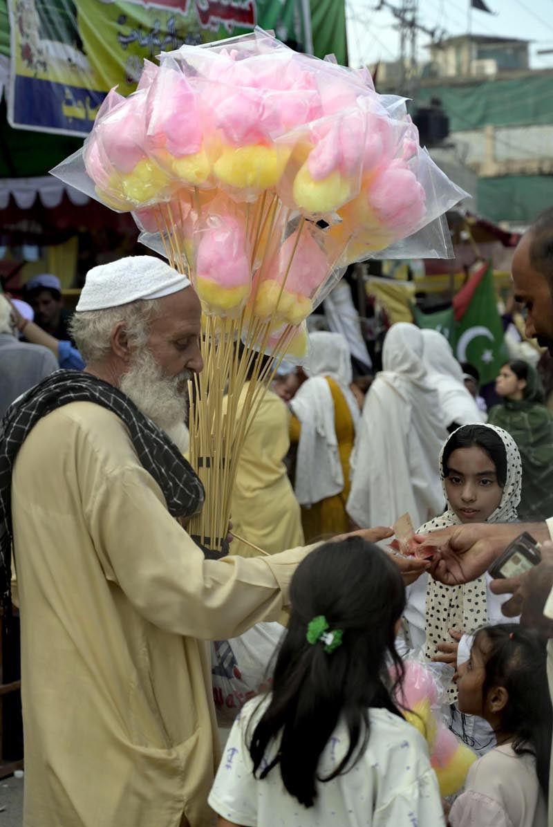 An elderly vendor sells cotton candy at Raja Bazar to earn a livelihood for his family in twin cities
