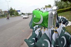 A vendor arranged and displayed children's clothes containing Pakistani flags to attract customers at a stall along the Expressway as part of Independence Day celebrations