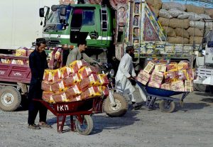 Daily-wage workers unload freshly delivered fruit boxes at the Fruit and Vegetable Market in federal capital