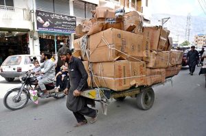 A labourer pulling handcart loaded with luggage to deliver in a local market.