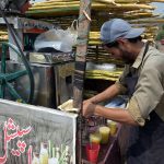 A vendor prepares fresh sugarcane juice at his roadside stall to quench the thirst of customers amid hot weather
