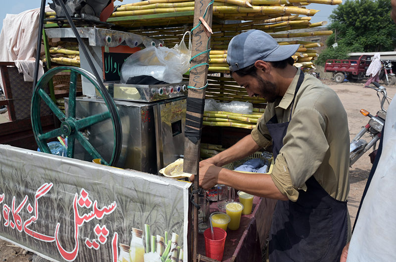A vendor prepares fresh sugarcane juice at his roadside stall to quench the thirst of customers amid hot weather