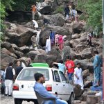 Families are enjoying the water flowing through the stones while visiting a water spring in the city during pleasant weather