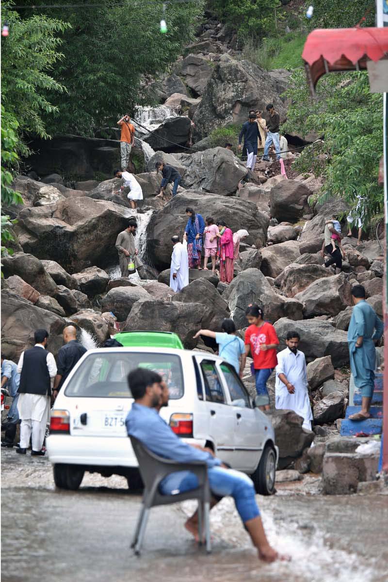 Families are enjoying the water flowing through the stones while visiting a water spring in the city during pleasant weather