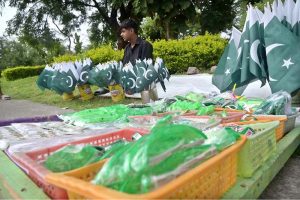 A vendor arranged and displayed children's clothes containing Pakistani flags to attract customers at a stall along the Expressway as part of Independence Day celebrations
