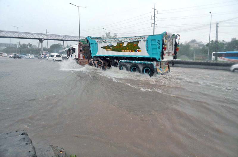 Vehicles passing through rain water accumulated on IJP Road after heavy rainfall in the Federal Capital