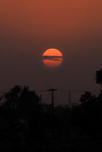 A mesmerizing sunset casts golden-orange hues across the sky, creating a picturesque view over the city.