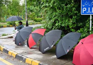A vendor displays colorful umbrellas to attract customers for selling at his roadside setup in Federal Capital