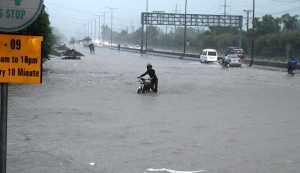 Vehicles passing through rain water accumulated on IJP Road after heavy rainfall in the Federal Capital