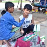 A youngster paints the face of a boy with the colors of the national flag in connection with the upcoming Independence Day celebrations