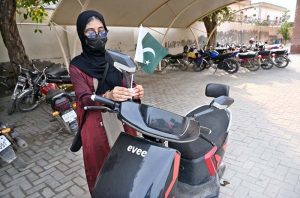 A girl is fixing a Pakistani flag on her electric scooty at the Sports Gymnasium in connection with the upcoming Independence Day celebrations.