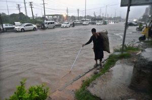 Vehicles passing through rain water accumulated on IJP Road after heavy rainfall in the Federal Capital
