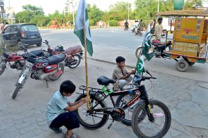 Children install Pakistani flags on their bicycles at Azadi Chowk as part of Independence Day celebrations.