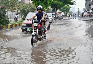 Vehicles navigate through rainwater accumulated on a road following heavy rainfall in PWD Society of the federal capital.
