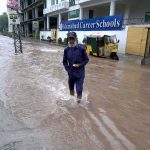 A person passing through rain water accumulated on road after heavy rain that experienced the Federal Capital