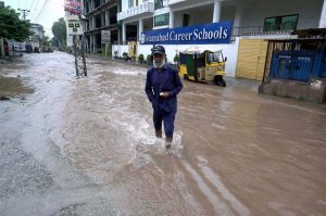 A person passing through rain water accumulated on road after heavy rain that experienced the Federal Capital