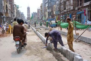 Labourers install cement blocks for traffic diversion near the newly constructed Aminpur Bazaar.