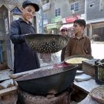 A young vendor busy roasting corn for customers at his roadside setup in Ghouri Town
