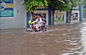 A person passing through rain water accumulated on road after heavy rain that experienced the Federal Capital