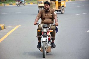 A law enforcement personnel rides a motorcycle without a number plate or helmet near the police lines, in violation of traffic regulations.