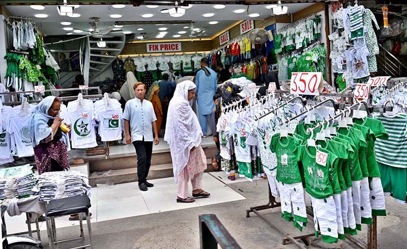 People are busy selecting and purchasing children's clothes containing Pakistani flags outside a shop at Bohar Bazaar in connection with Independence Day celebrations