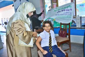 A lady health worker administers an anti-polio booster dose to a child during an anti-polio vaccination campaign at Air Foundation School.