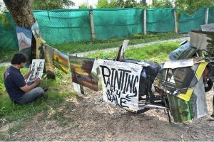 A painter is busy at work, creating a painting to sell along the roadside in the Federal Capital