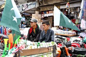 People are busy selecting and purchasing children's clothes containing Pakistani flags outside a shop at Bohar Bazaar in connection with Independence Day celebrations
