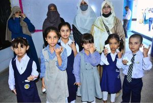 A lady health worker administers an anti-polio booster dose to a child during an anti-polio vaccination campaign at Air Foundation School.
