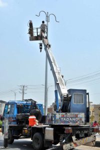 A worker is busy repairing a street light using a hydraulic lift on City Road during maintenance work.