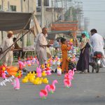 A family purchases colorful toys for a child from a roadside vendor at a temporary stall in the city