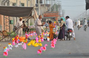 A family purchases colorful toys for a child from a roadside vendor at a temporary stall in the city
