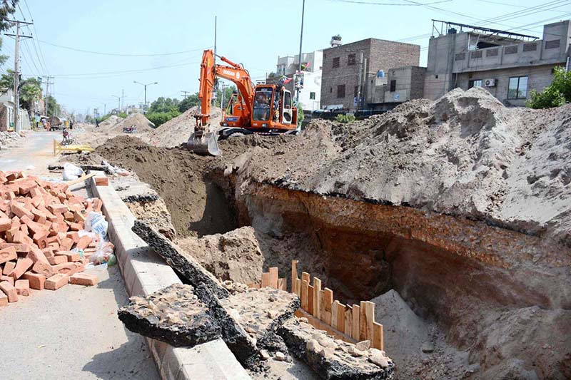 Workers fill the dug-up area with heavy machinery after laying the sewerage pipeline during ongoing development work in Mumtazabad