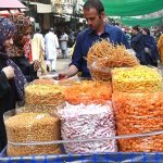 Women buy roasted beans, lentils and traditional food items from vendor at Delhi Gate