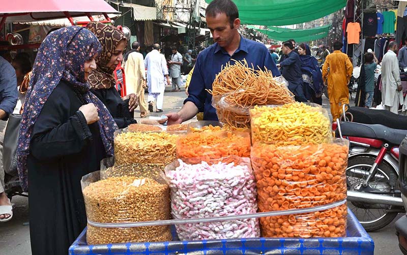 Women buy roasted beans, lentils and traditional food items from vendor at Delhi Gate