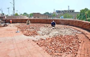 Labourers are busy crushing bricks to prepare material for the floor.