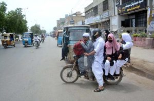 A man rides a motorcycle carrying schoolchildren as educational institutions reopen after the summer vacation.